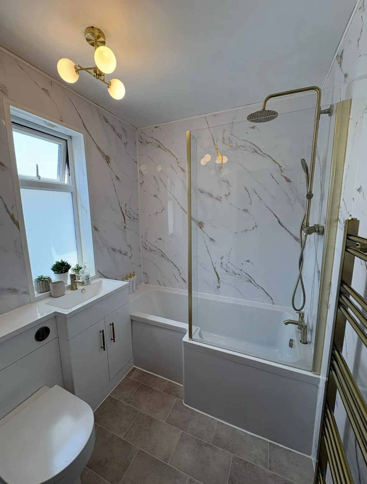 Freshly cleaned bathroom with marble-effect shower panels and bath